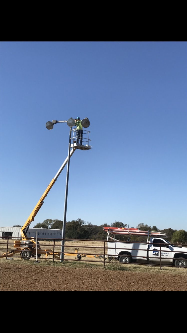 Xtreme Electric technician in a bucket truck installing a pole light fixture near Stephenville, TX.
